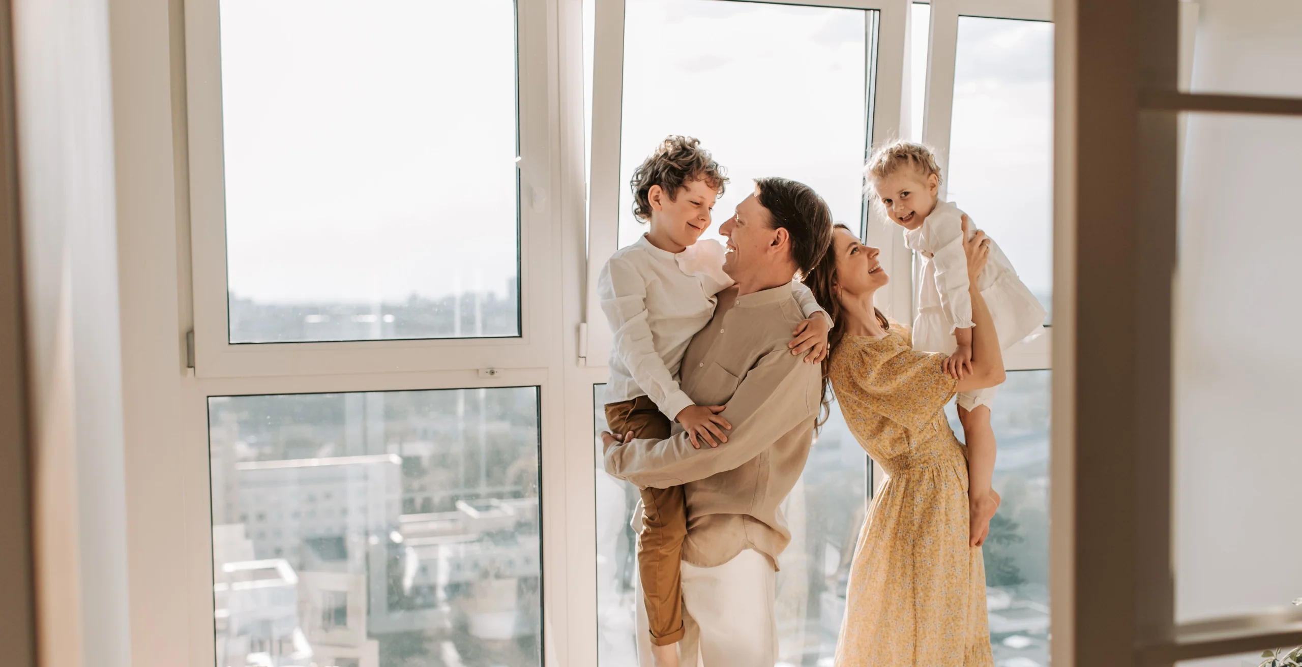 A family holding one another in a sunlit room at home